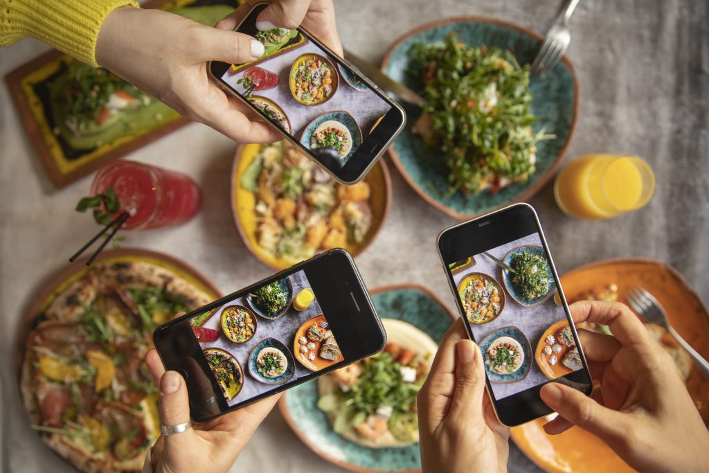 manos haciendo fotos de comida en un restaurante